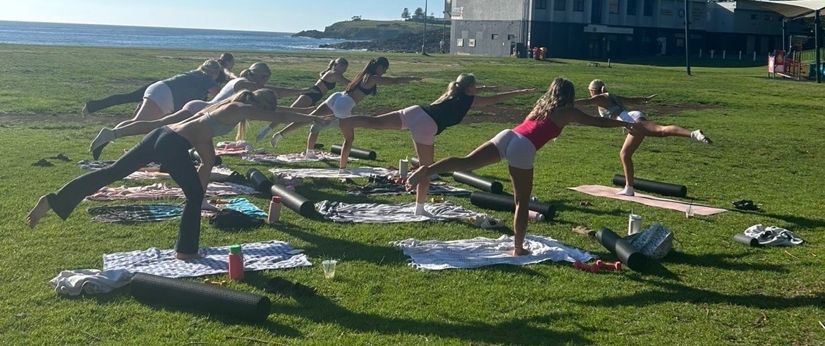 Amber leading an outdoor pilates session by the coast